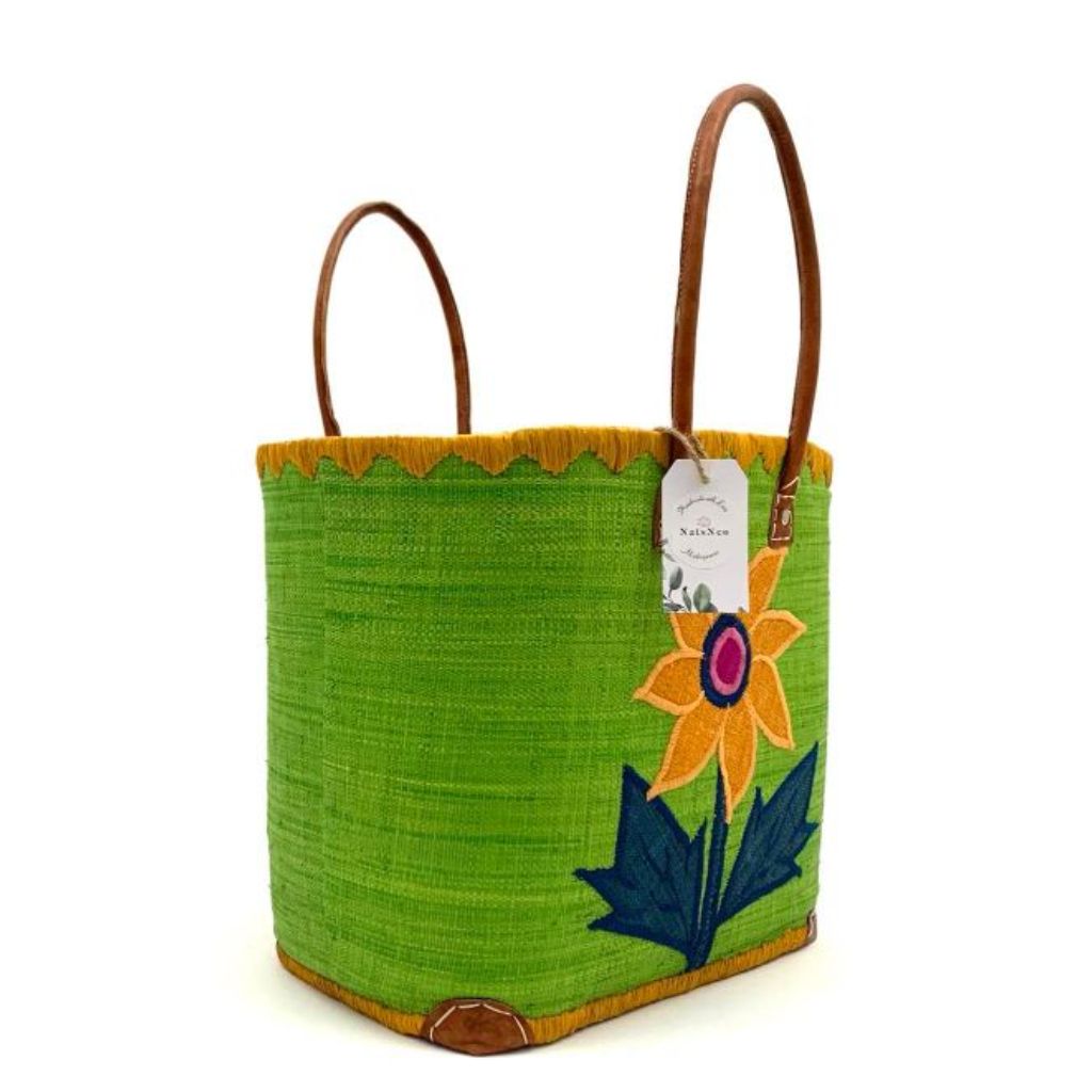 Green raffia basket with sunflower embroidery on the front and back. It has a leather handle. Handmade with love in Madagascar.